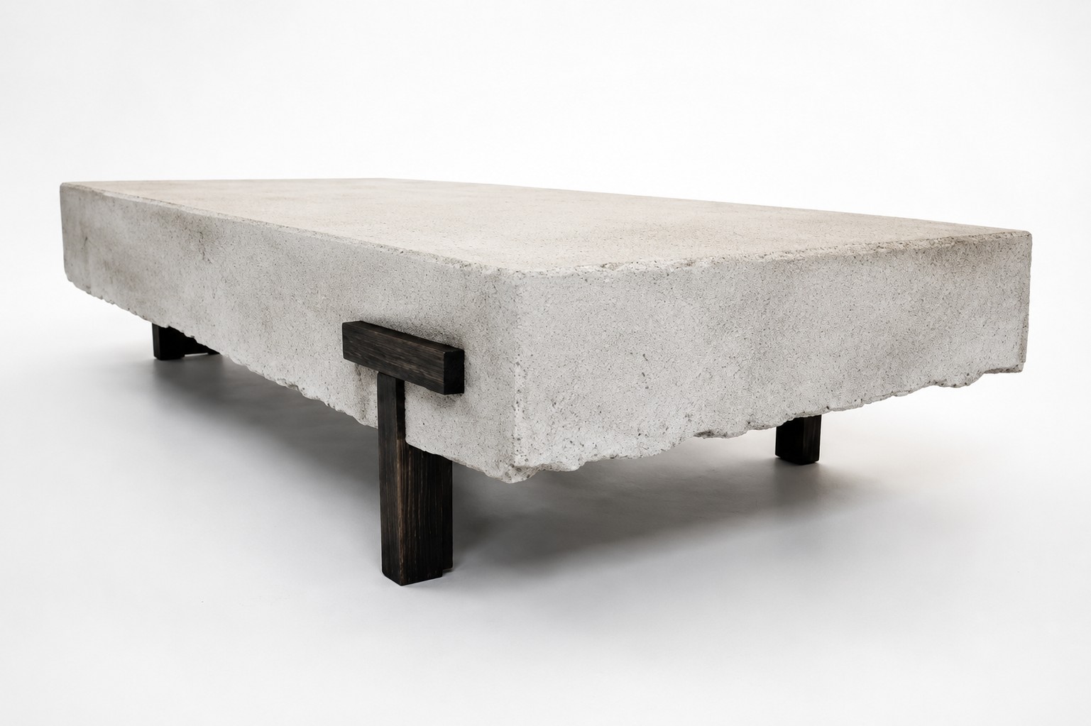 Three-quarter view of PIEZA 001 showing the mineral-finish slab top and the joinery where the dark wooden leg meets the underside.